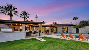 Une terrasse extérieure moderne dotée d’une piscine, de chaises longues et d’un espace barbecue.