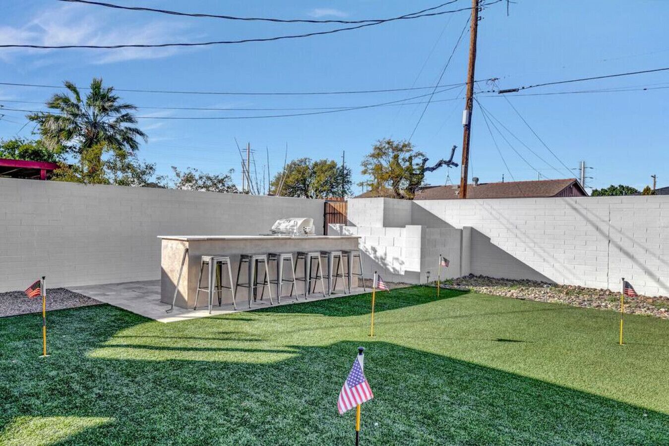 A backyard with a barbecue area, a white wall, and a flag.