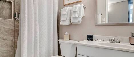 A bathroom with a shower, toilet, and sink.