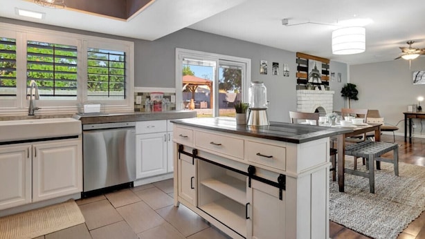 Une cuisine moderne avec des meubles blancs, un grand îlot central et des luminaires suspendus.