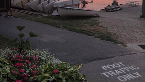 Une vue sur le front de mer, avec des bateaux amarrés, une plage de sable et un ciel dégagé.