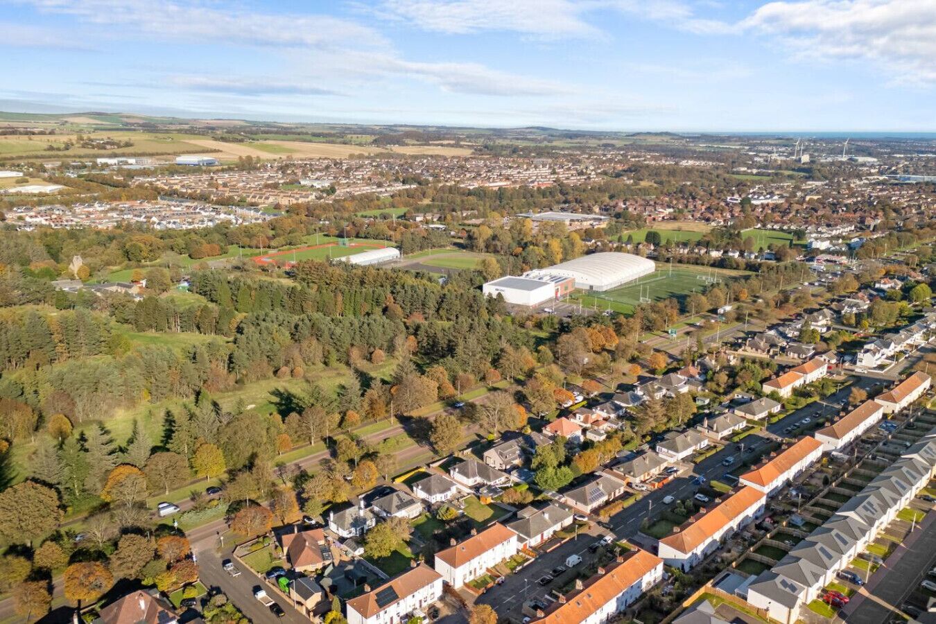 An aerial view of a residential area with houses, a large sports field, and a stadium.