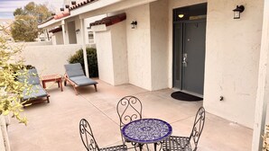 Eine Terrasse mit einem runden Tisch, vier Stühlen, zwei Liegestühlen und einer Tür mit der Nummer 42.