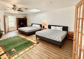A bedroom with two beds, a ceiling fan, a skylight, a green and red rug, and a wooden floor. - 42-Resort Condo, Pool, Hot Tub, Pickle-ball, Gym. (St. George)
