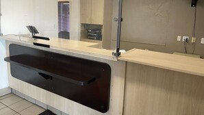 Een receptiebalie met een flatscreen televisie, een klok en een raam met zonwering.