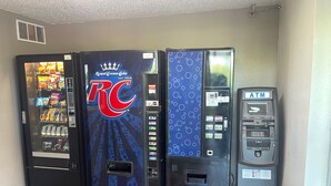 Een rij automaten, waaronder een Royal Crown Cola automaat, een automaat met een blauw patroon en een geldautomaat.