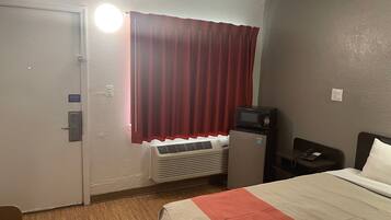 Een hotelkamer met een bed, een bureau, een magnetron en een verwarming.