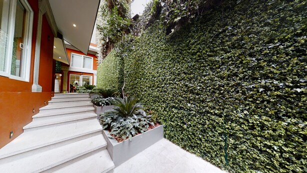 Ein modernes Gebäude mit einer Treppe, die zu einer Tür führt, umgeben von einer gepflegten Hecke.