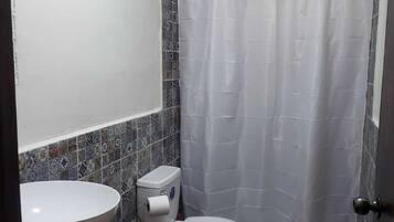 Un bagno con lavandino bianco, toilette e tenda per la doccia.