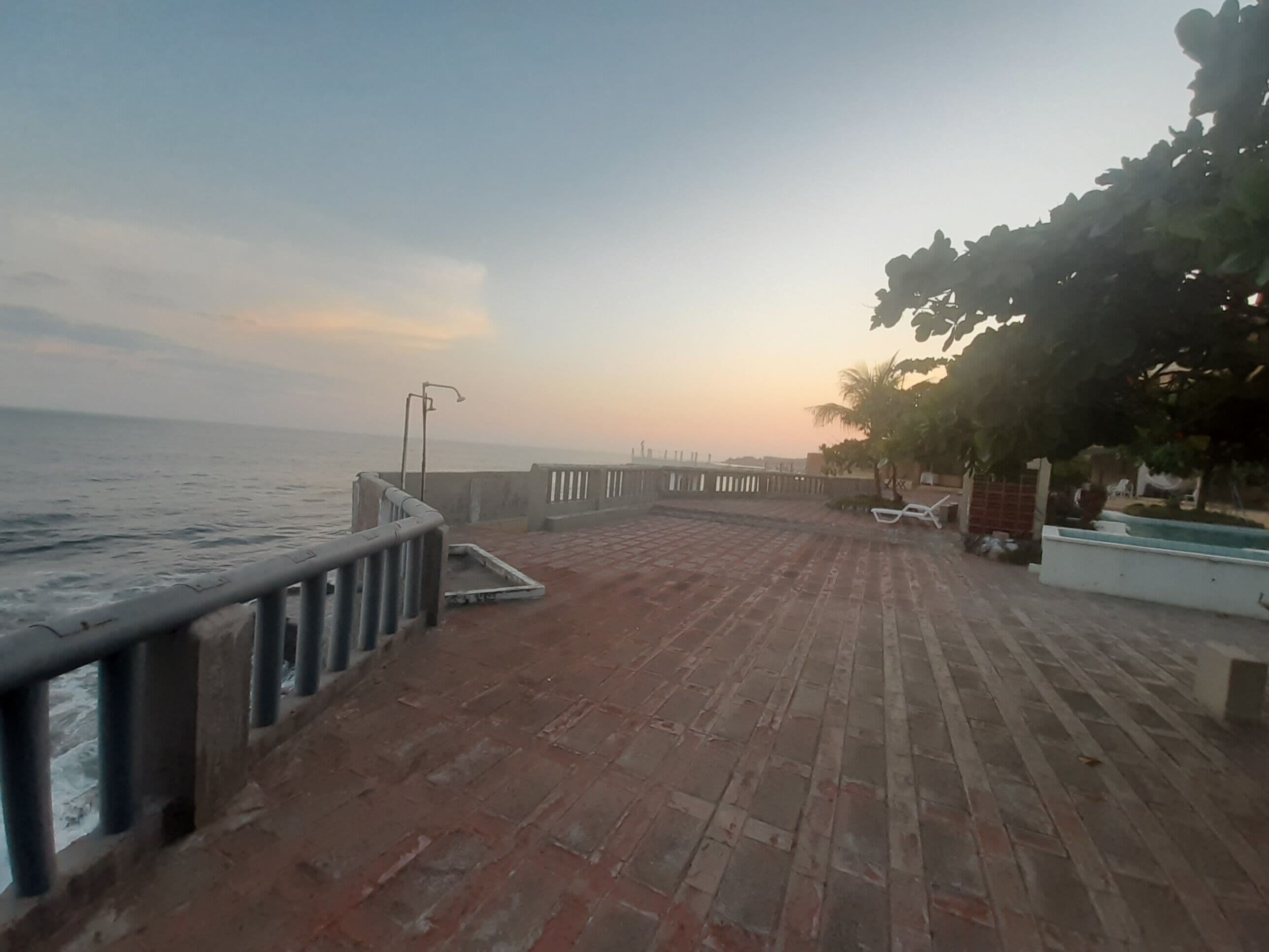 Une terrasse en bois avec une rambarde donnant sur la mer.