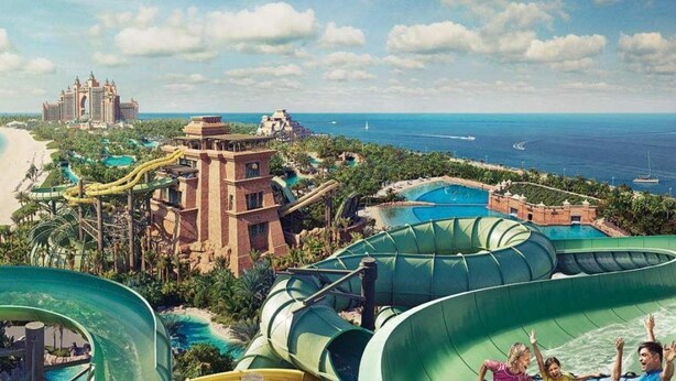 Un resort con un parque acuático grande, una playa y una estructura hotelera con aspecto de castillo.