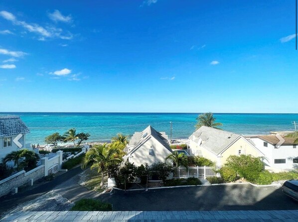 A coastal residential area with houses, a clear blue sky, and a view of the ocean.