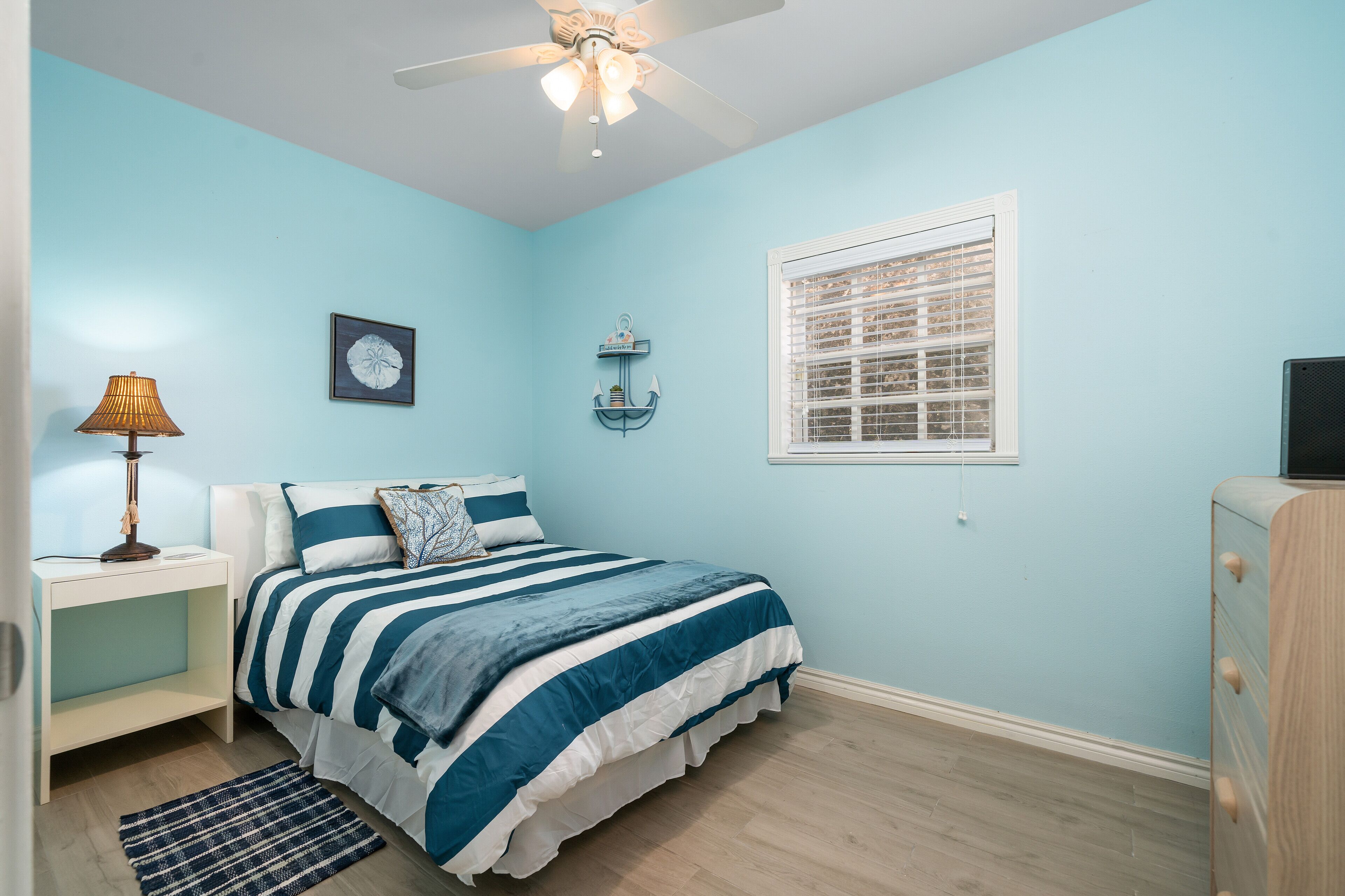 A bedroom with a bed, nightstand, lamp, and a ceiling fan.