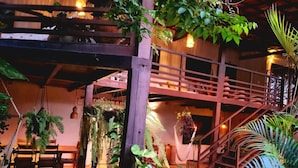 A rustic interior with a wooden staircase, hanging plants, and a cozy seating area. - Villa Valencia (Jijoca de Jericoacoara)