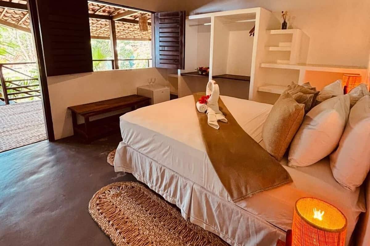 Ein Schlafzimmer mit einem Bett, Nachttischlampen, einer Bank und einer gewebten Matte.