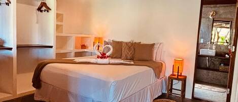 A bedroom with a bed, bedside table, hanging clothes rack, and a small stool.