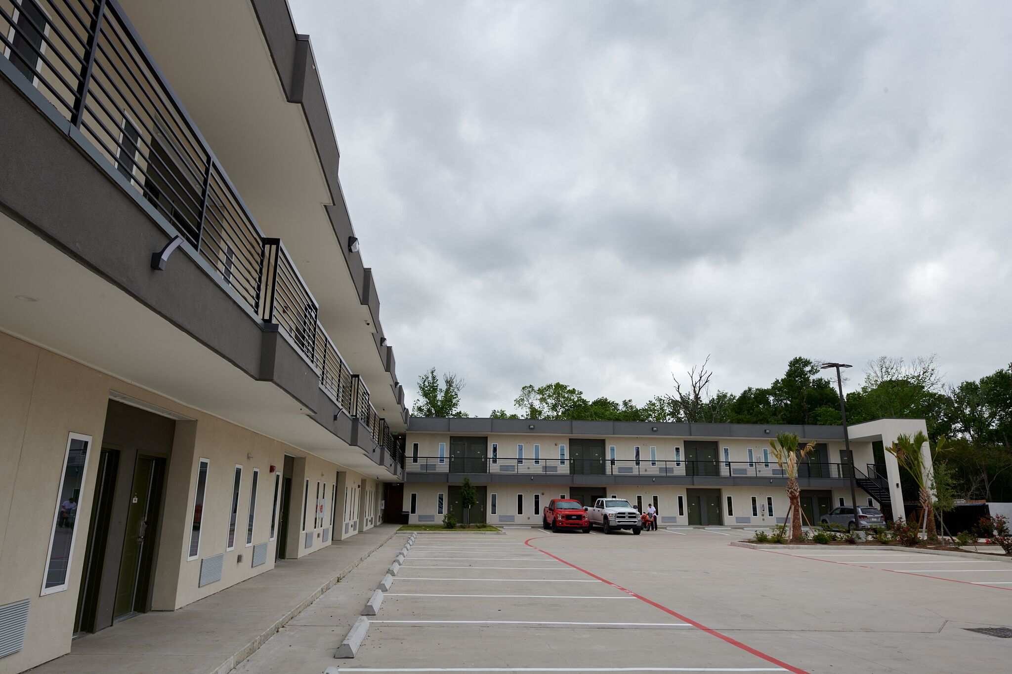A modern building with a parking lot, multiple entry doors, and a staircase leading to the upper floors.