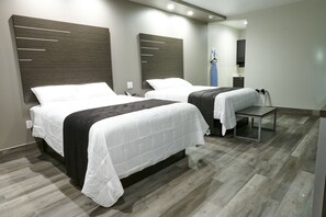 A hotel room with two beds, a small table, and a mirror.