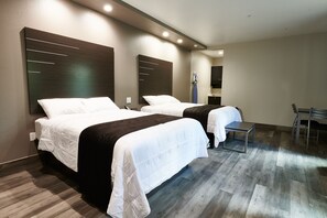 A hotel room with two beds, a desk, and a chair.