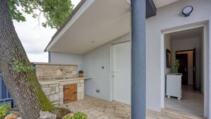 A stone-floored outdoor area with a built-in sink and a door leading to an interior space. - Apartment Mirjana for two people, quiet location, barbecue, pets welcome (Fažana)