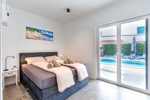 Un dormitorio con cama, mesita de noche y un cuadro de una escena de playa.