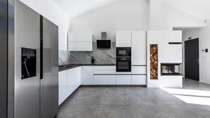 A modern kitchen with stainless steel appliances, white cabinetry, and a marble backsplash. - Villa Larra with heated pool & Jacuzzi (Gostinjac (Krk))