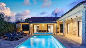 A modern house with a swimming pool, stone walls, and a patio area with lounge chairs. - Villa Larra with heated pool & Jacuzzi (Gostinjac (Krk))