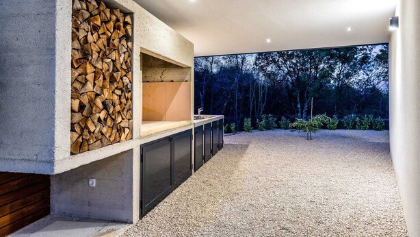 A modern kitchen with a built-in wood storage and a large window overlooking a forest. - Villa Larra with heated pool & Jacuzzi (Gostinjac (Krk))