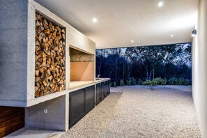 A modern kitchen with a built-in wood storage and a large window overlooking a forest. - Villa Larra with heated pool & Jacuzzi (Gostinjac (Krk))