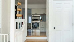 Una cocina moderna con armarios blancos, un horno de acero inoxidable y una lámpara colgante.