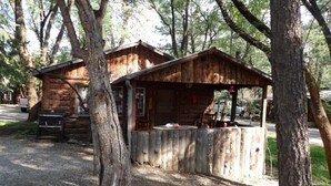 Eine rustikale Holzhütte mit Veranda und einer kleinen Sitzgelegenheit im Freien.