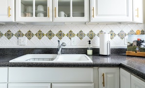 A kitchen with white cabinets, a granite countertop, a sink, and a decorative backsplash. - Bluff Row. Historic Row Home in Cathedral Square. Downtown Dubuque. (Dubuque)