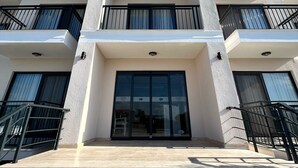 A multi-story building with a modern architectural design, featuring balconies, large windows, and a central entrance with glass doors. - DADA OTEL (Ezine)