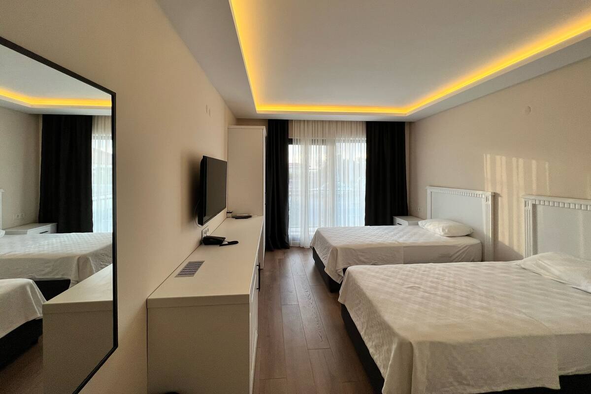 Habitación de hotel con dos camas, televisor, escritorio y espejo.