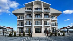 A multi-story building with balconies, a tiled entrance area, and a clear sky. - DADA OTEL (Ezine)