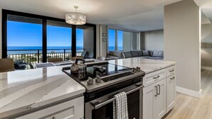 Een moderne keuken met een groot schiereiland, een fornuis en uitzicht op zee.