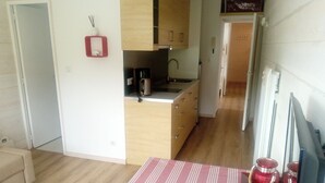 A modern kitchen with wooden cabinets, a coffee maker, and a sink. There is a striped table with a remote control on it.