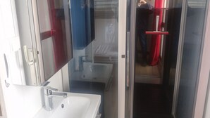 A bathroom with a sink, mirror, and glass door leading to a shower area.