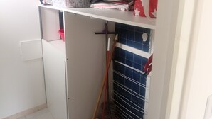A small, enclosed utility room with a white door, a blue tiled wall, and a broom leaning against it.