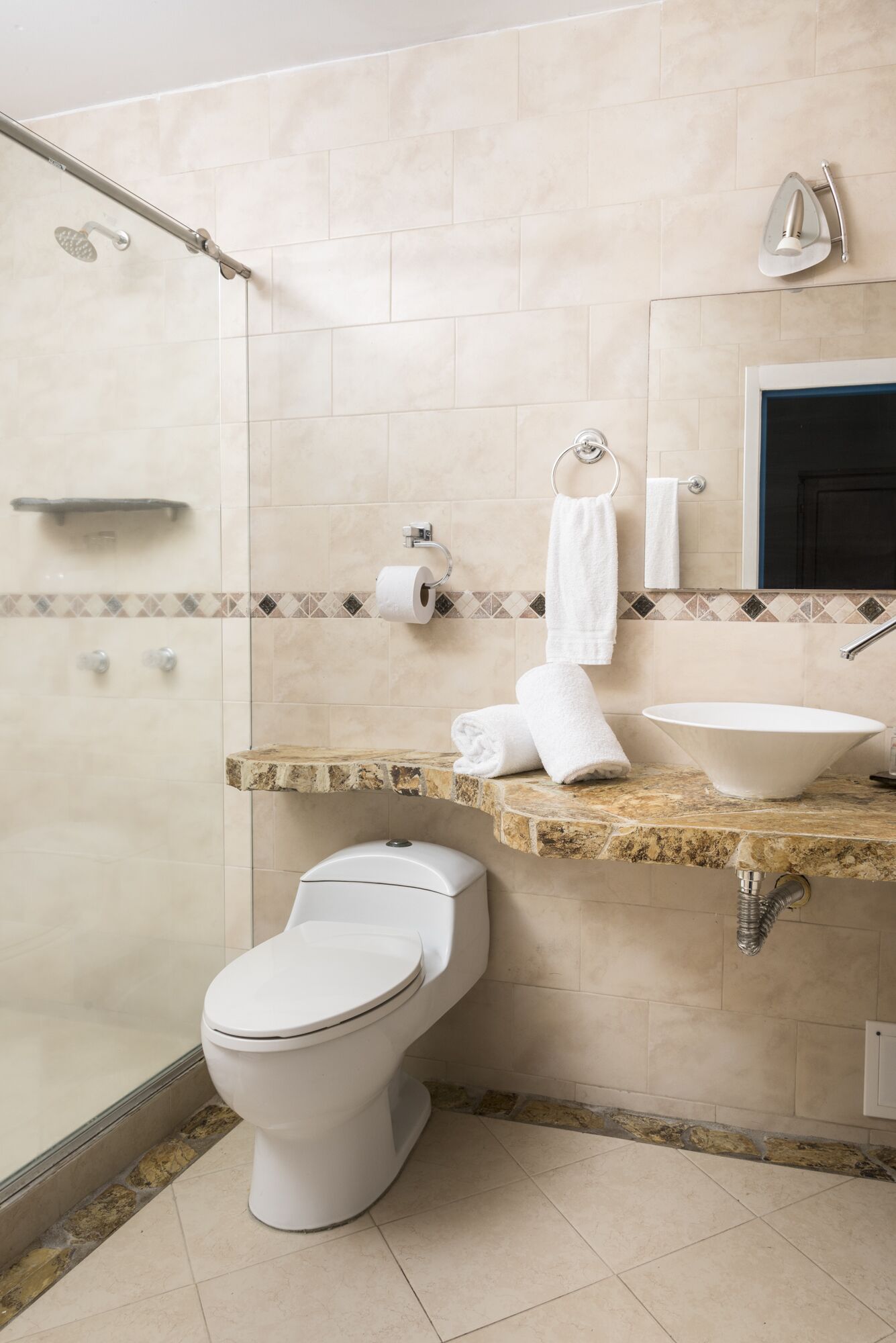 A modern bathroom with a shower, toilet, and sink.