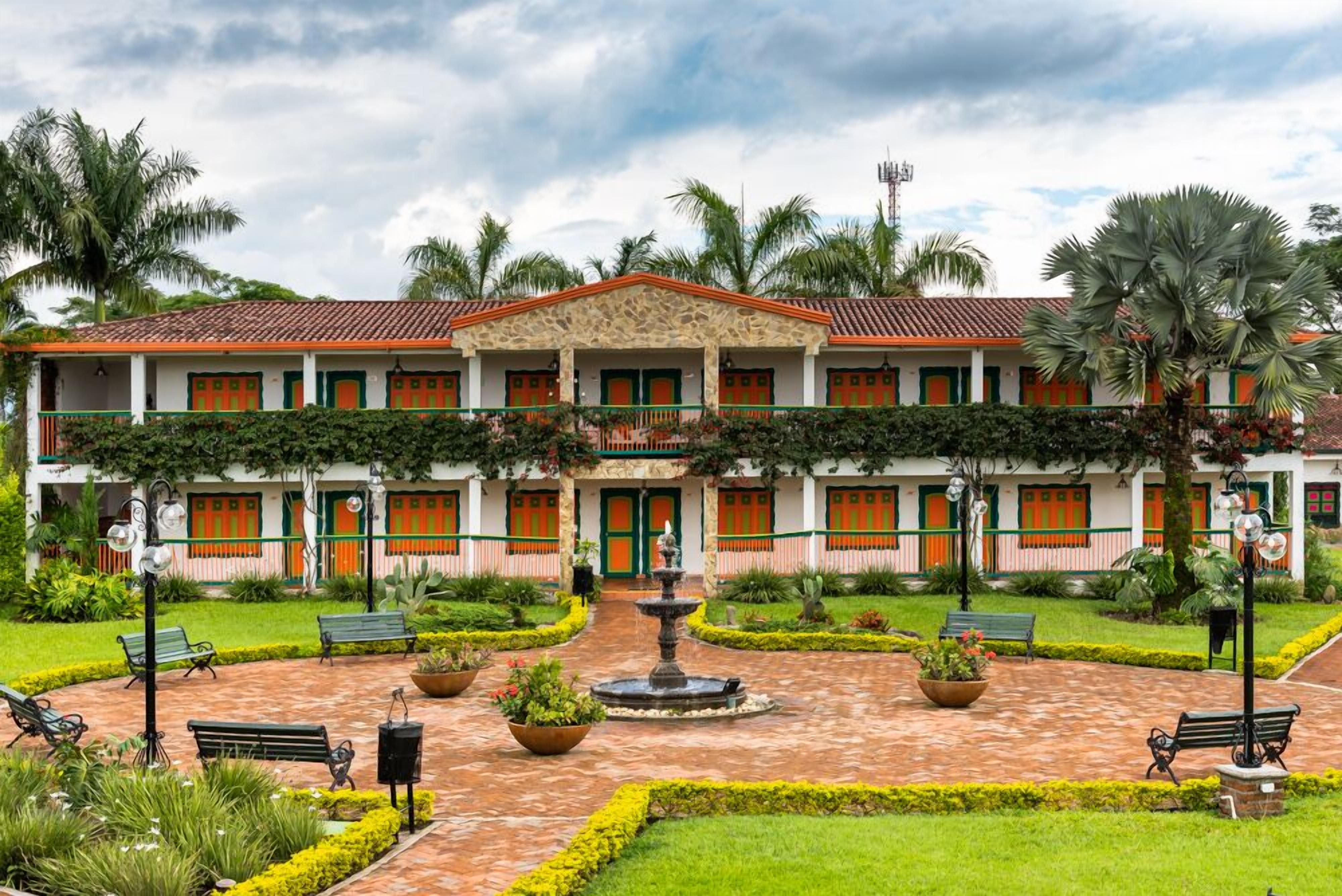 A two-story building with a central courtyard, featuring a fountain, benches, and well-maintained gardens.