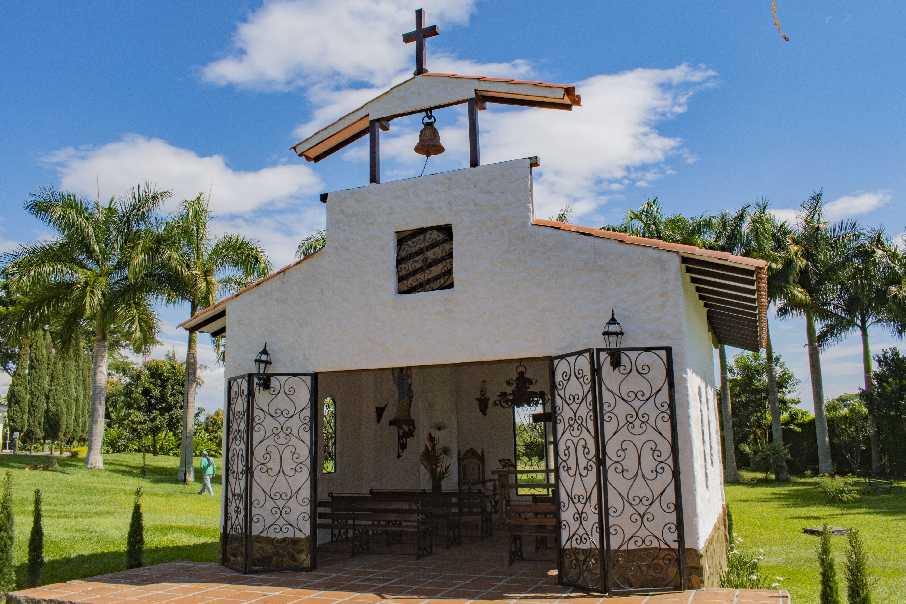 A small church with a bell tower, a cross, and a bell.