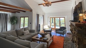 Un salon spacieux avec une cheminée en pierre, un grand canapé et une table basse.