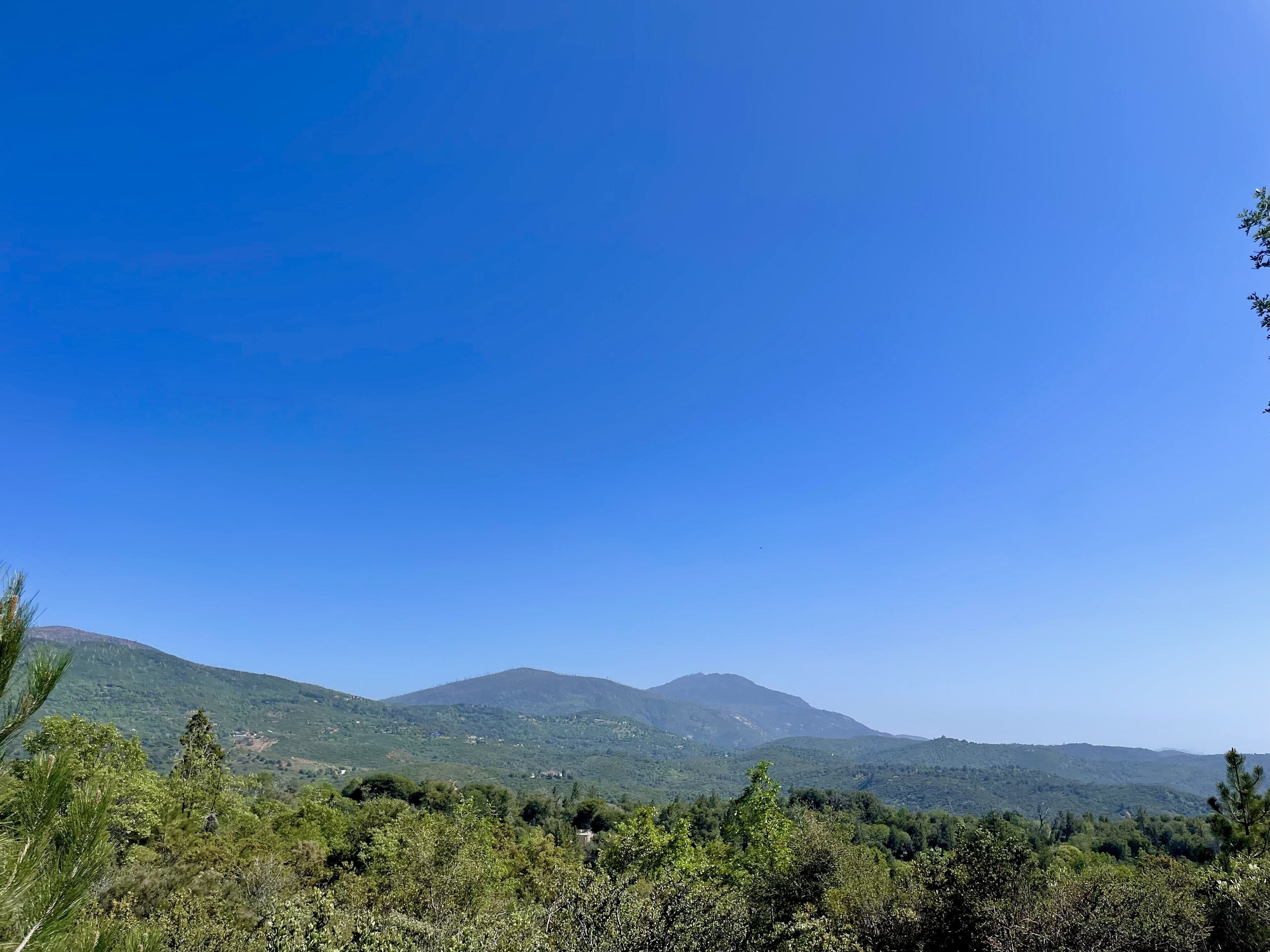 A mountainous landscape with dense greenery and clear blue sky.
