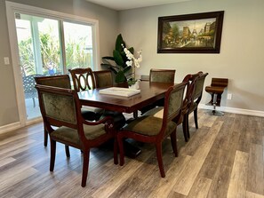 A dining room with a wooden table and chairs, a vase with flowers, and a painting on the wall. - House in San Diego #2 (San Diego)