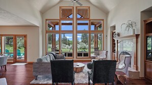 Un amplio salón con techo alto, ventanas grandes y chimenea.