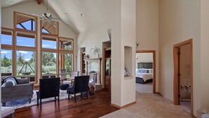 Amplia sala de estar con techos altos, ventanas grandes y vistas al exterior.