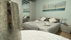Ein Schlafzimmer mit Bett, Nachttisch, Lampe und einem Meereslandschaftsbild.