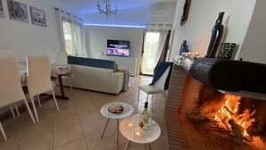 Ein Wohnzimmer mit Kamin, Fernseher und einem Essbereich mit Stühlen und Tisch.