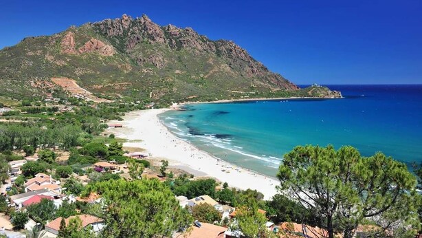 Eine Küstenstadt mit einem markanten Berg, einem Strand und Wohngebäuden.